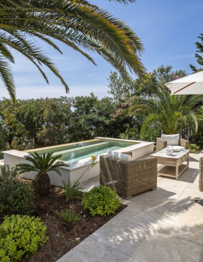 Renovated terrace with outdoor furniture, palm trees and small pool overlooking the sea