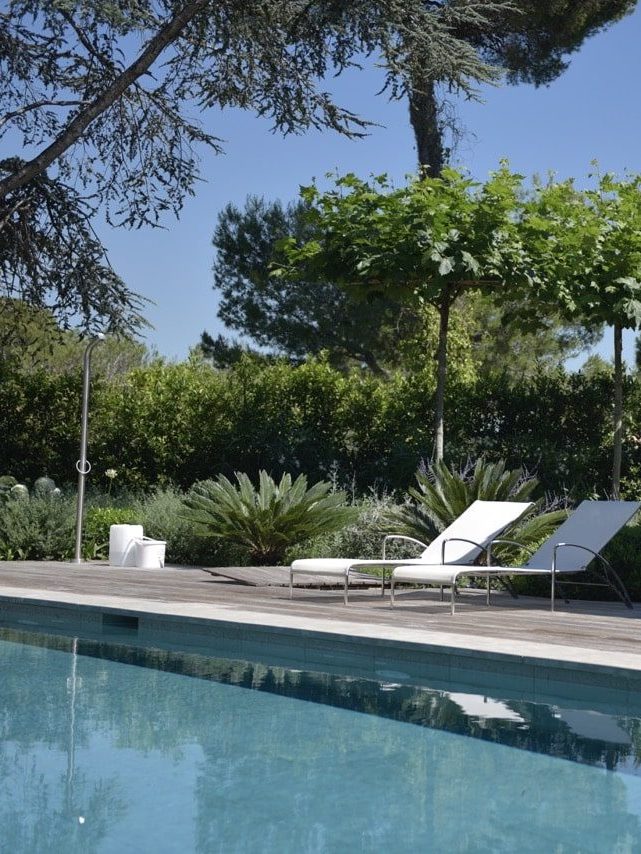 Bains de soleil sur une terrasse en bois devant une piscine