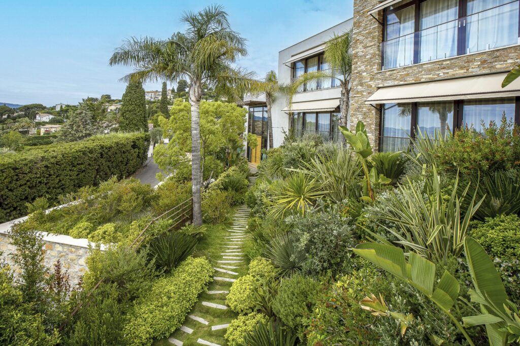 Jardin en pente luxuriant avec vue sur la maison moderne en hauteur