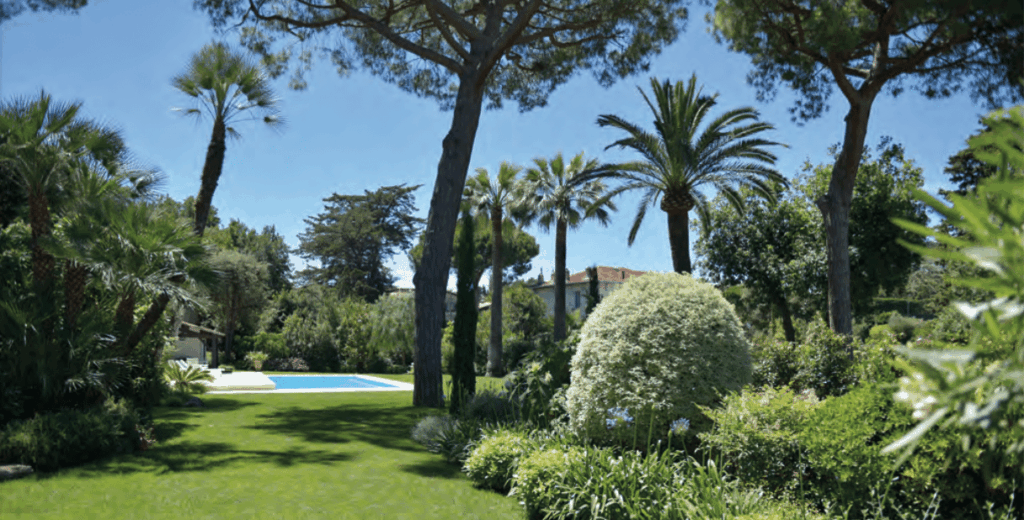 Jardin luxuriant parsemé d'art topiaire, piscine en arrière plan