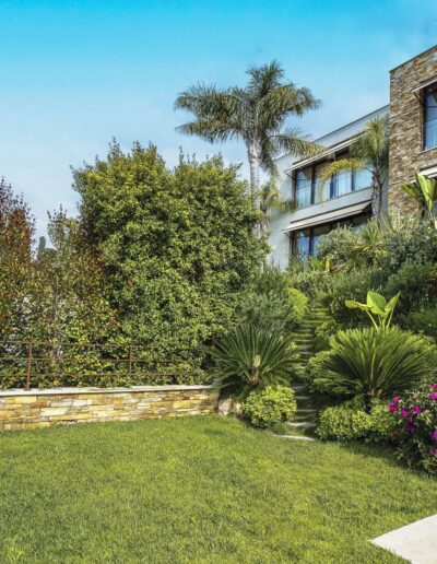 Massifs fleuris et végétation tropicale au pied d’une maison contemporaine.