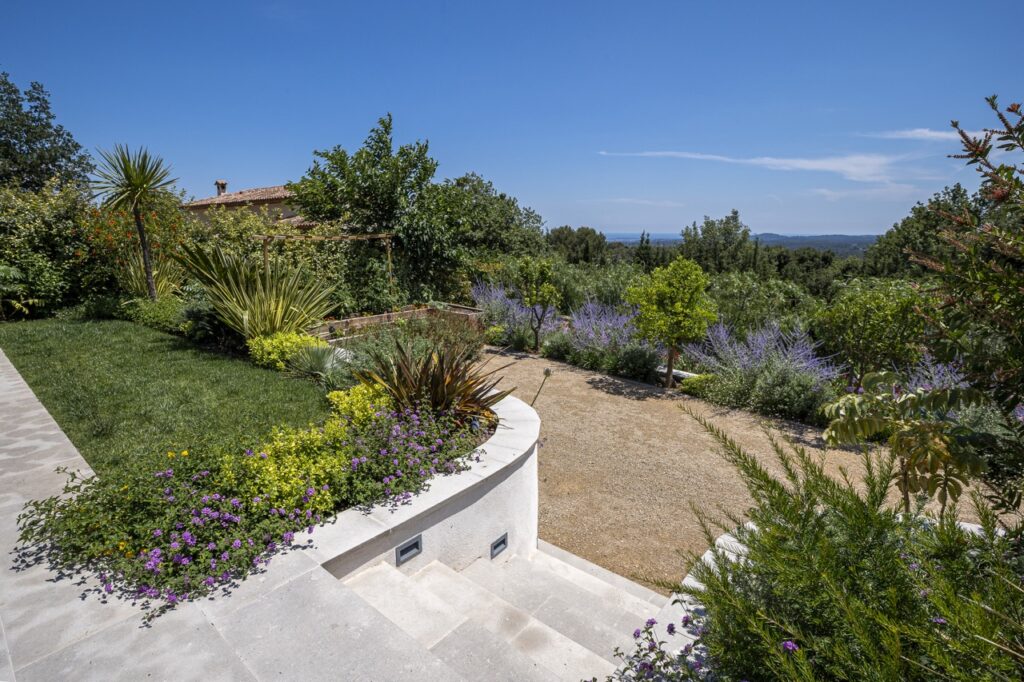 Gravel pathway bordered by colorful Mediterranean plantings with landscape view