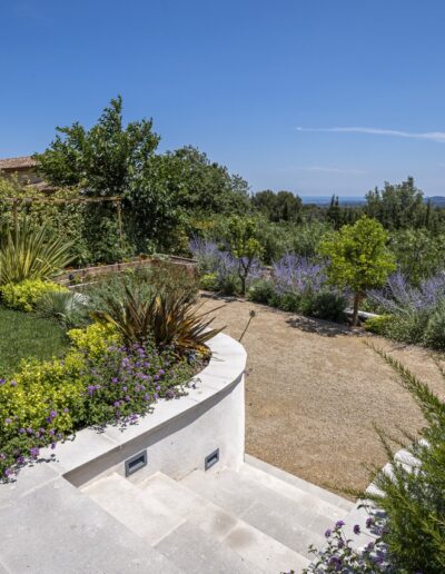Gravel pathway bordered by colorful Mediterranean plantings with landscape view