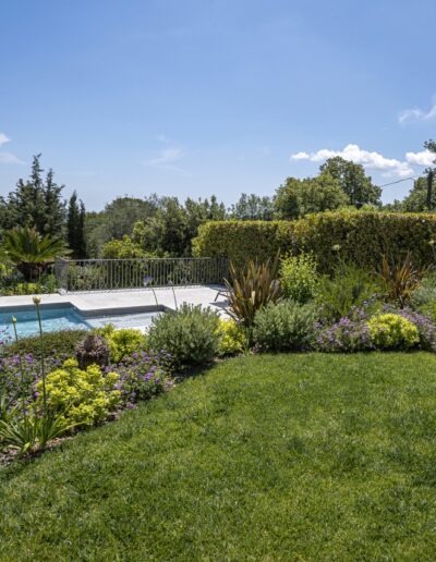 Pool surrounded by Mediterranean plants and flower beds with countryside view