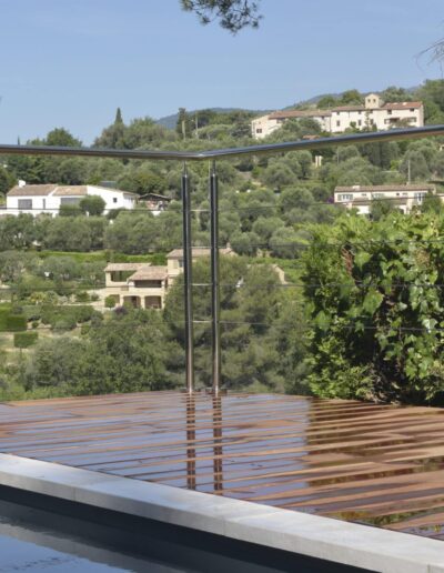 Metal railing on a wooden deck overlooking tree-covered hills