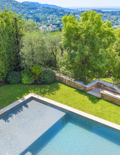 Aerial view of the garden with pool and large trees overlooking the Bay of Cannes.