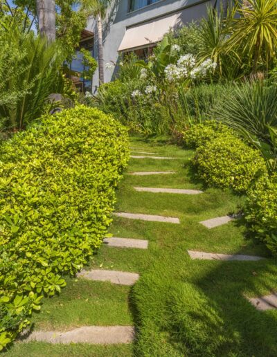 Pedestrian pathway integrated into a lush garden with natural lines and abundant planting.