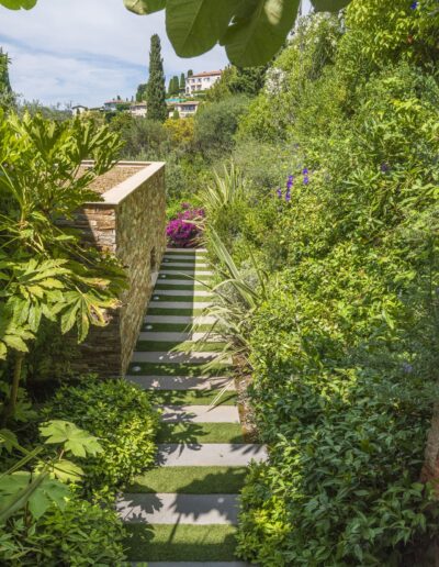 Landscaped staircase bordered by stone walls and dense, colorful vegetation.