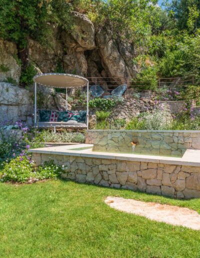 Aménagement paysager finalisé avec bassin en pierre, muret et plantes méditerranéennes