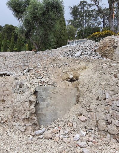 Stone terraces under renovation with a partially collapsed wall and rubble at the base