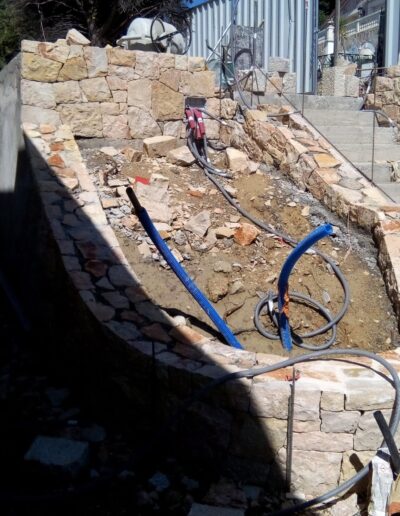 Construction of a stone retaining wall along a slope during garden development.