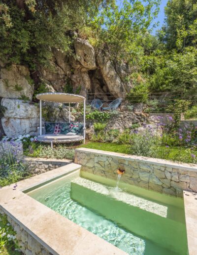 Stone pool inspired by a traditional washhouse, set within a Mediterranean garden