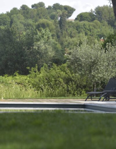 Pool surrounded by loungers, shrubs and lush summer greenery