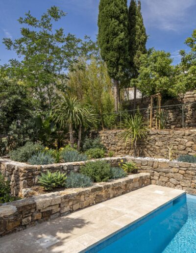 Terraced garden with stone walls and Mediterranean planting beside the pool