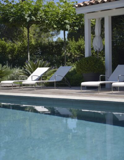 Transats blancs modernes sur une terrasse en bois, avec haie végétale en arrière-plan