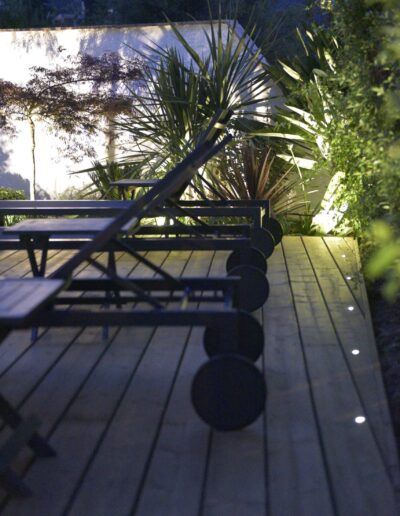 Alignement de transats sur une terrasse en bois avec éclairage latéral intégré