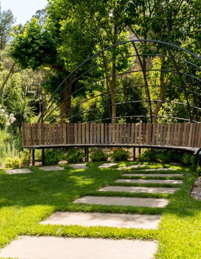Curved bench under a metal pergola in the heart of a natural garden in Mougins