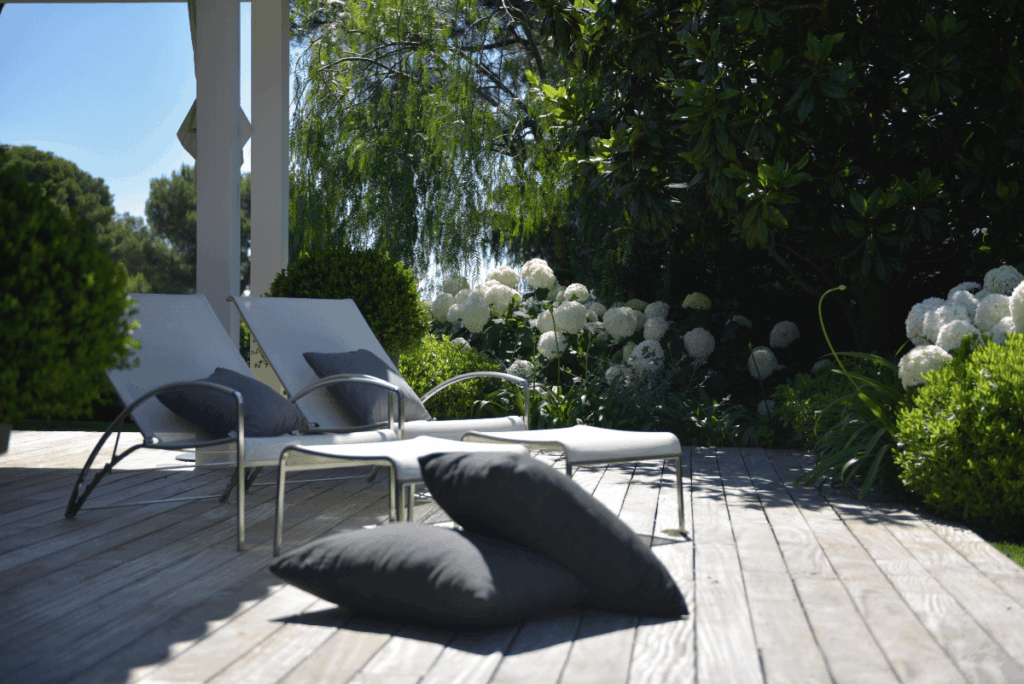 Sun loungers on a wooden terrace bordered with plants