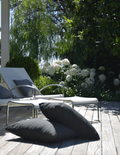 Sun loungers on a wooden terrace bordered with plants